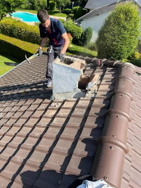 Artisan couvreur intervenant sur un pied de cheminée et vérifiant l’étanchéité pour empêcher les fuites dans les Yvelines