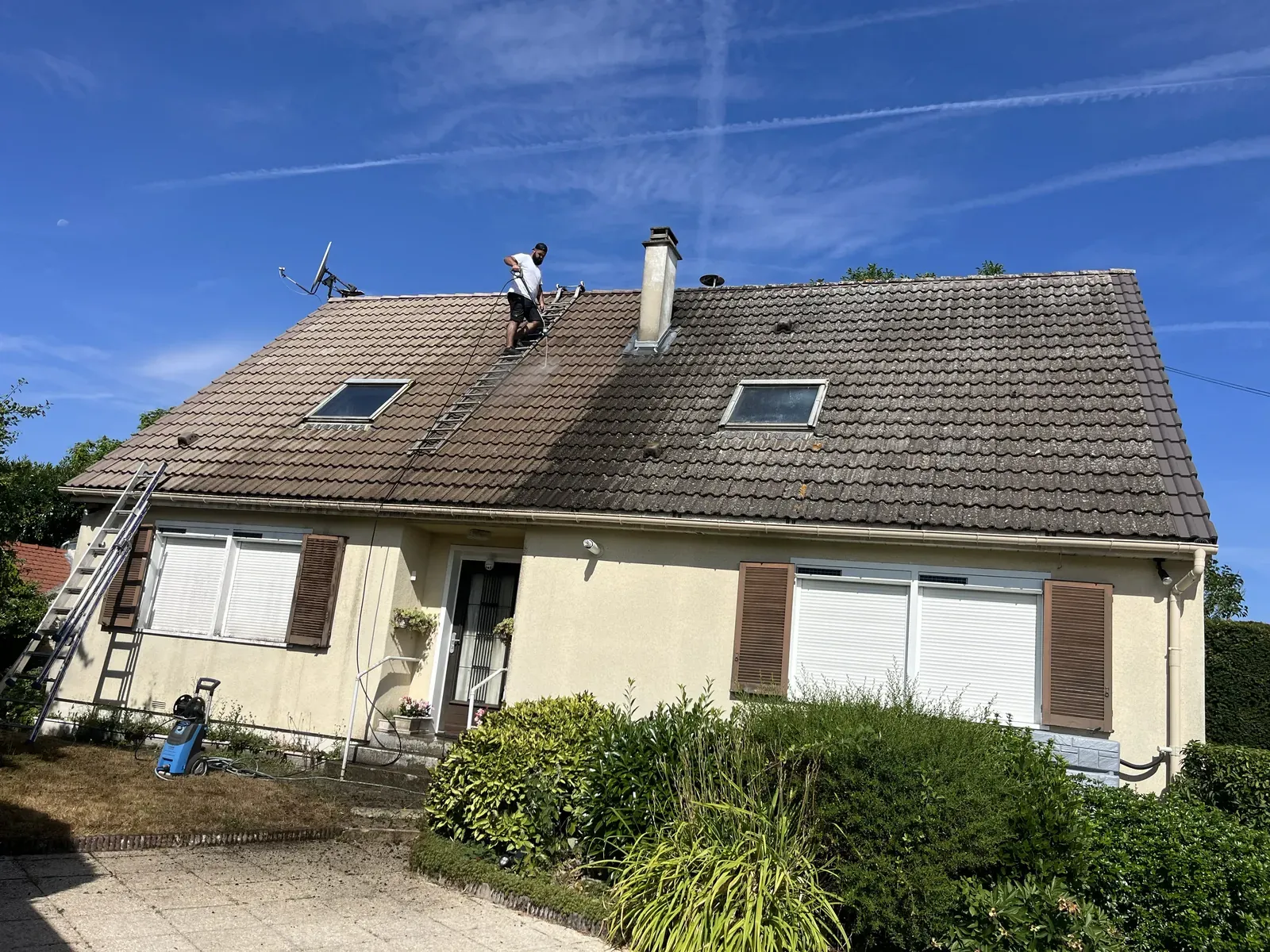 Nettoyage au Karcher d’une toiture en tuiles béton à Rambouillet : contraste entre les tuiles nettoyées et les tuiles encore encrassées
