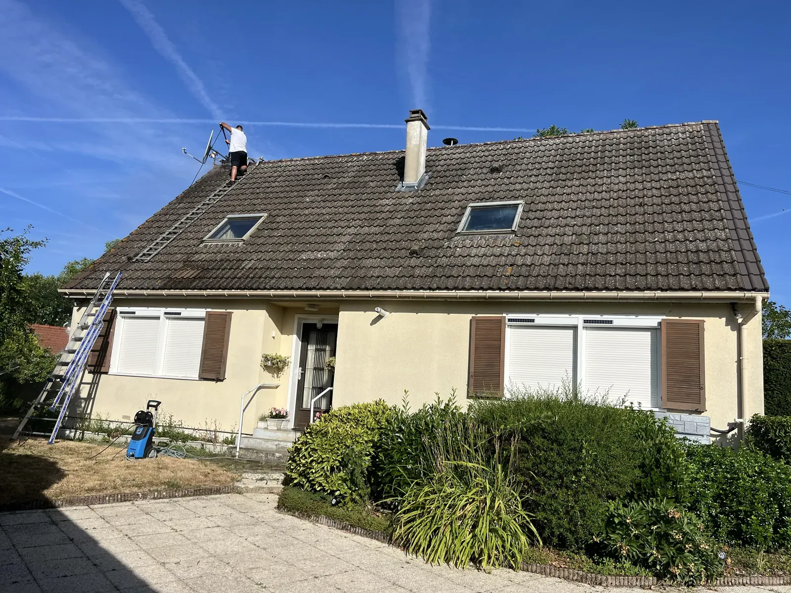 Début du nettoyage haute pression d’une toiture en tuiles béton couverte de mousse à Rambouillet